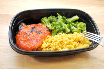 A Meal of a Chicken Thigh with Catalina Dressing Baked on Top, Yellow Rice and Steamed Broccoli