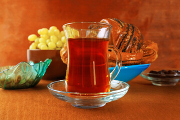 Elegant mug of tea with poppy seed rolls and grapes on plates on boards