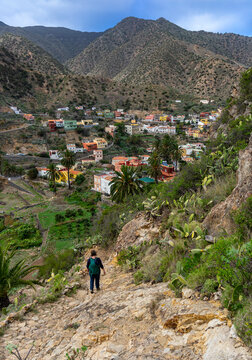 VALLEHERMOSO, LA GOMERA, Kanarische Inseln: Wanderung von einer Frau im Norden der Insel mit Blick von oben auf den pittoresken Ort mit bunten Häusern und den Bergen