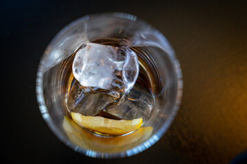 Ein leeres Glas von oben fotografiert mit einem Eiswürfel und einer Zitrone