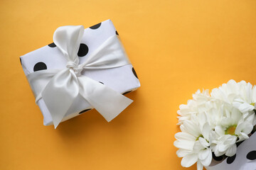 bouquet of white chrysanthemums on a yellow background and a gift box 