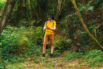 Caucasian man typing with his smartphone phone in the jungle