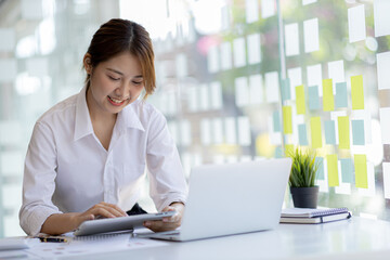 young businesswoman looking at financial information from a tablet, she is checking company financial documents, she is a female executive of a startup company. Concept of financial management.