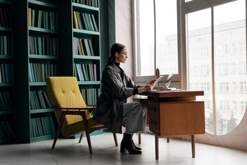 A woman with glasses, a financier, works in an office, uses a laptop, prints a message to the mail