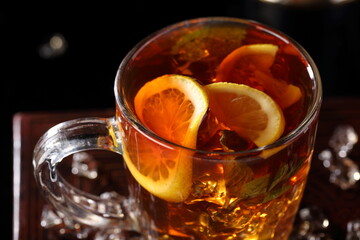 Black tea with ice cubes and mint on a black background