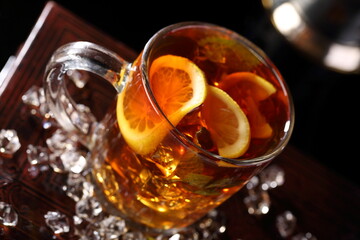 Black tea with ice cubes and mint on a black background