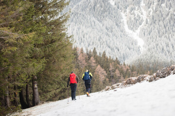 Fototapeta premium People hiking in beautiful winter mountains for winter sport activity snow mountain hills. Visit Piatra Craiului National Park to see its iconic rocky monolith winter hiking