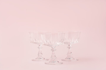 Three vintage crystal glasses for sparkling wine or champagne on pastel pink background.Summer drink concept. Minimal creative composition with copy space.