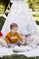 Handsome caucasian man holding baby boy on shoulders while smiling to charming woman outdoors. Happy young parents with lovely son playing near teepee tent among green nature. © sofiko14