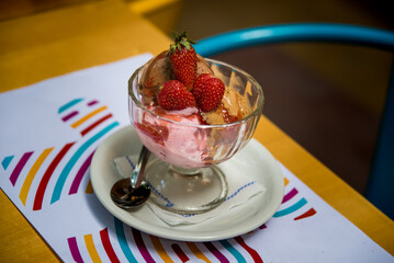 glass of ice cream with strawberries on a plate on a wooden table