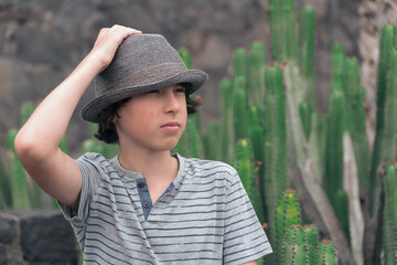 Portrait of a teenager in a polo shirt and a hat against the background of cacti.