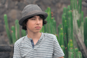 Portrait of a teenager in a polo shirt and a hat against the background of cacti.
