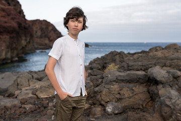 Portrait of a teenager on the background of a rocky ocean shore.