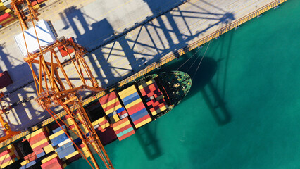 Aerial top down photo of cranes loading - unloading container ship anchored in logistics terminal...
