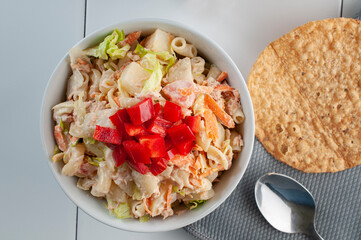 Macro photography, tuna salad with lettuce mayo carrot strips and red peppers on top with a spoon and a tostada on the side, flat lay top view or lay flat 