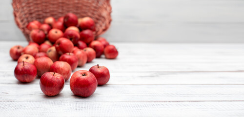 jabłka w wiklinowym koszu na rustykalnym tle białych desek