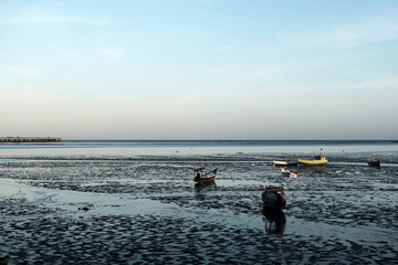 Small fishing boats reflected in the low tide