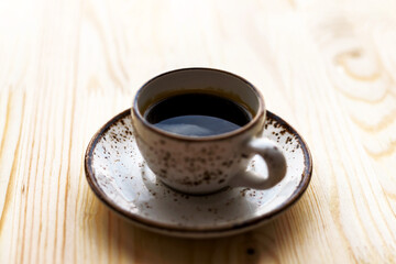 Cup of Coffee espresso on saucer on wooden table background. Sunny morning breakfast concept.