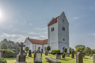 a white swedish church with a high tower, in the soft sunshine,