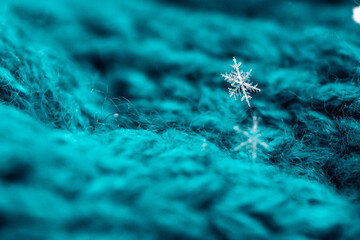 A snowflake sits on a teal scarf