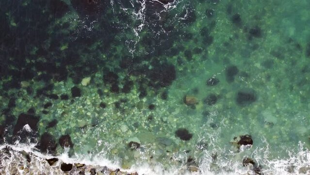 Aerial view of waves breaking on the rock beach. Drone filming of sea 