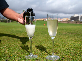 Celebration of championship with glasses of champagne bubbles wine on green lawn of golf club