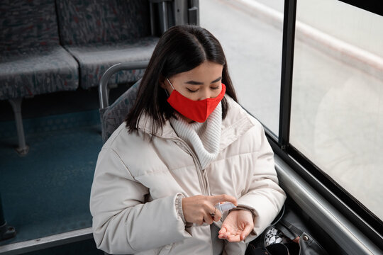Female passenger applying sanitizer in bus