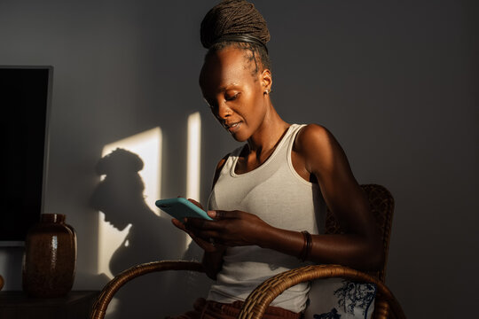 African woman browsing social media in armchair