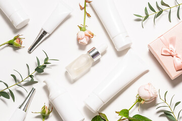 Set of natural organic skin care cosmetic products on white background with eucalyptus leaves and rose flowers top view
