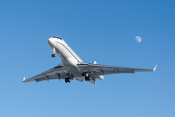 Fototapeta na wymiar business jet on final approach with the moon in the background