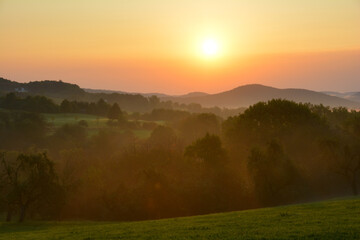 Morning fog at sunrise in a green landscape