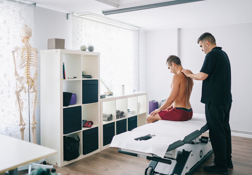 Physiotherapist massaging shoulders of patient