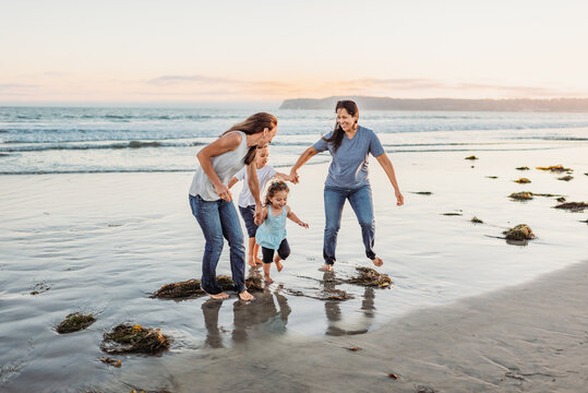Same-sex couple romps on beach with kids