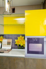 high-gloss kitchen in bright yellow with wood countertops and glass shelves and splashback with yellow daffodils 