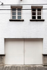 A minimal white exterior with two windows and a garage.