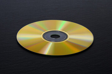 Golden CD disk on a black background. Black stone background.