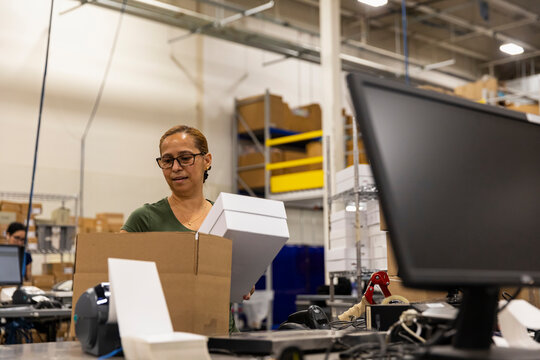 E-Commerce Worker packs white box for shipping 