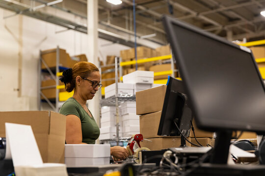 E-Commerce employee packs box for shipping 