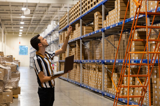 Warehouse worker counting boxes with  laptop computer