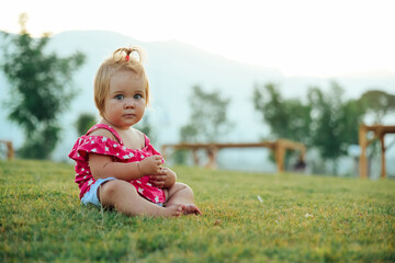 Adorable toddler girl sitting on the grass