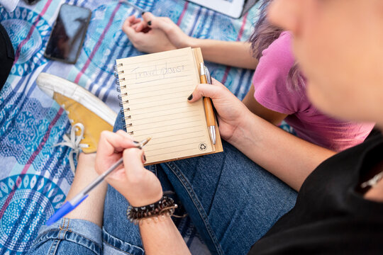 Teenager writing on notebook with friends