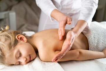 a woman gives a massage to a little girl, children's massage, prevention of scoliosis, osteopathy