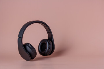 black headphones fly on a beige background, copy space