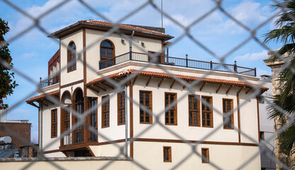 historical building behind an iron mesh. metal fence. adana, turkey. ilter uzel medical museum.