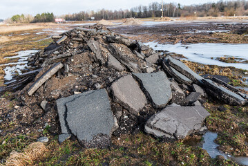 Broken old cracked asphalt after the road upgrade stacked in the heap on the ground to be recycled.