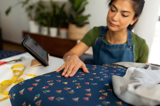 Asian woman upholstering cushion at home
