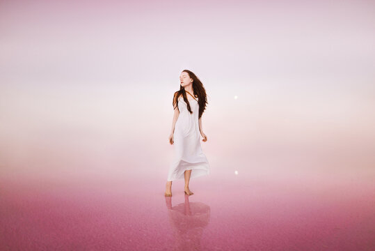 Red head woman in a white dress in the pink salt lake