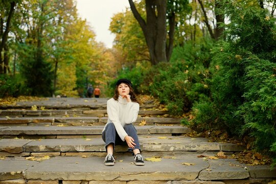 Woman sitting on the stairs to the park in autumn 
