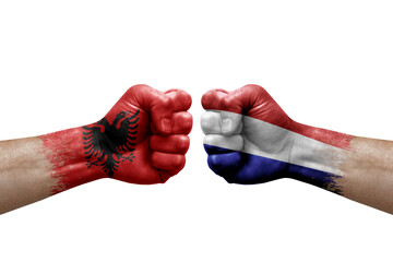 Two hands punch to each others on white background. Country flags painted fists, conflict crisis concept between albania and netherlands