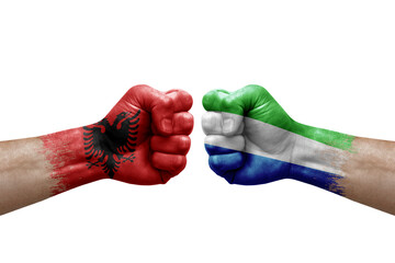 Two hands punch to each others on white background. Country flags painted fists, conflict crisis concept between albania and sierra leone